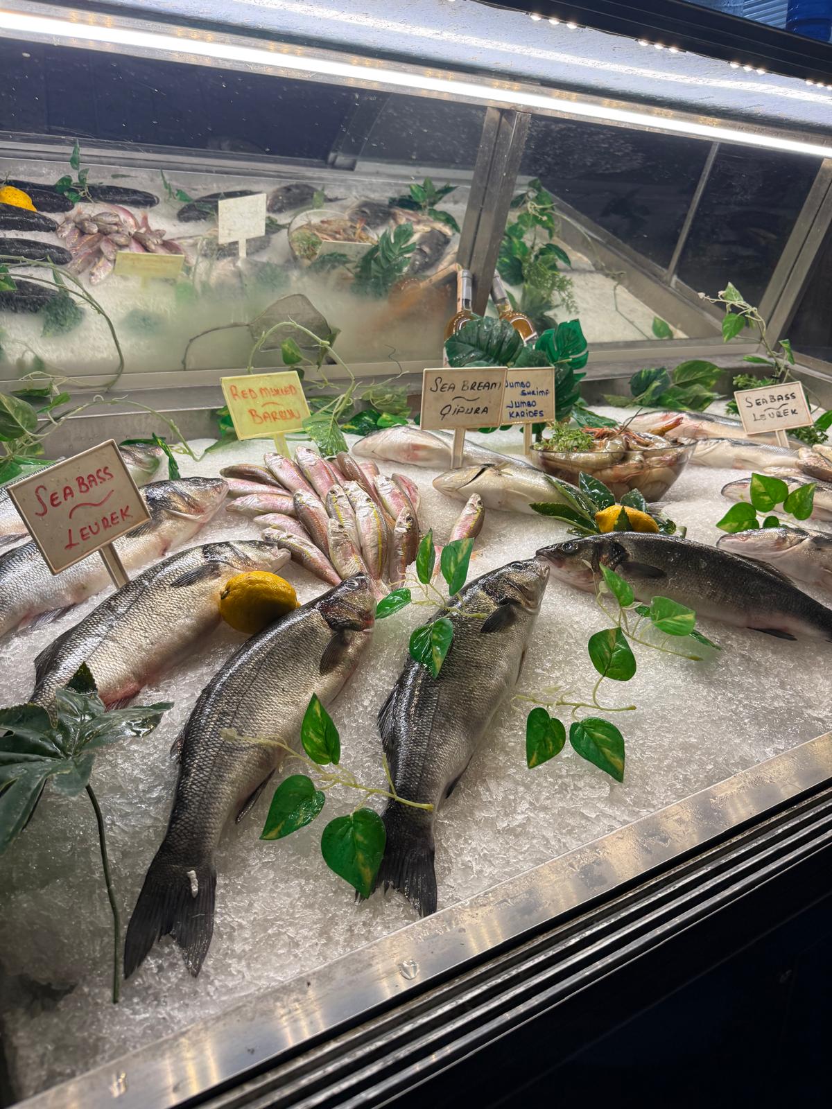 Fresh sea bass and bream arranged on ice at a premium retail counter.