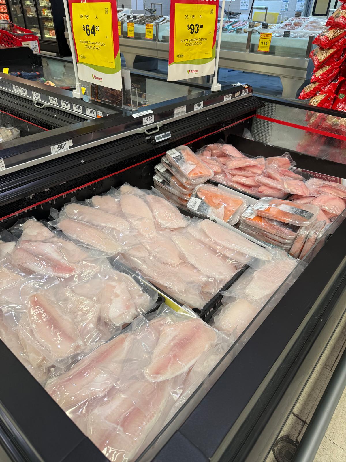 Vacuum-packed tilapia and salmon fillets in a modern supermarket case.